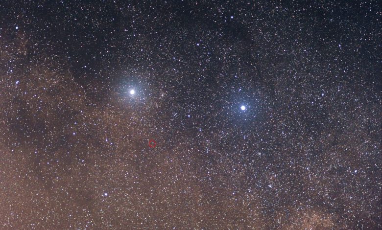 The two bright stars are (left) Alpha Centauri and (right) Beta Centauri. The faint red star in the center of the red circle is Proxima Centauri. Taken with Canon 85mm f/1.8 lens with 11 frames stacked, each frame exposed 30 seconds. Image Credit: Skatebiker / Wikimedia Commons.