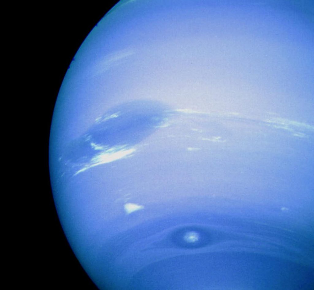 Neptune’s Great Dark Spot, accompanied by white high-altitude clouds. Image Credit: NASA.