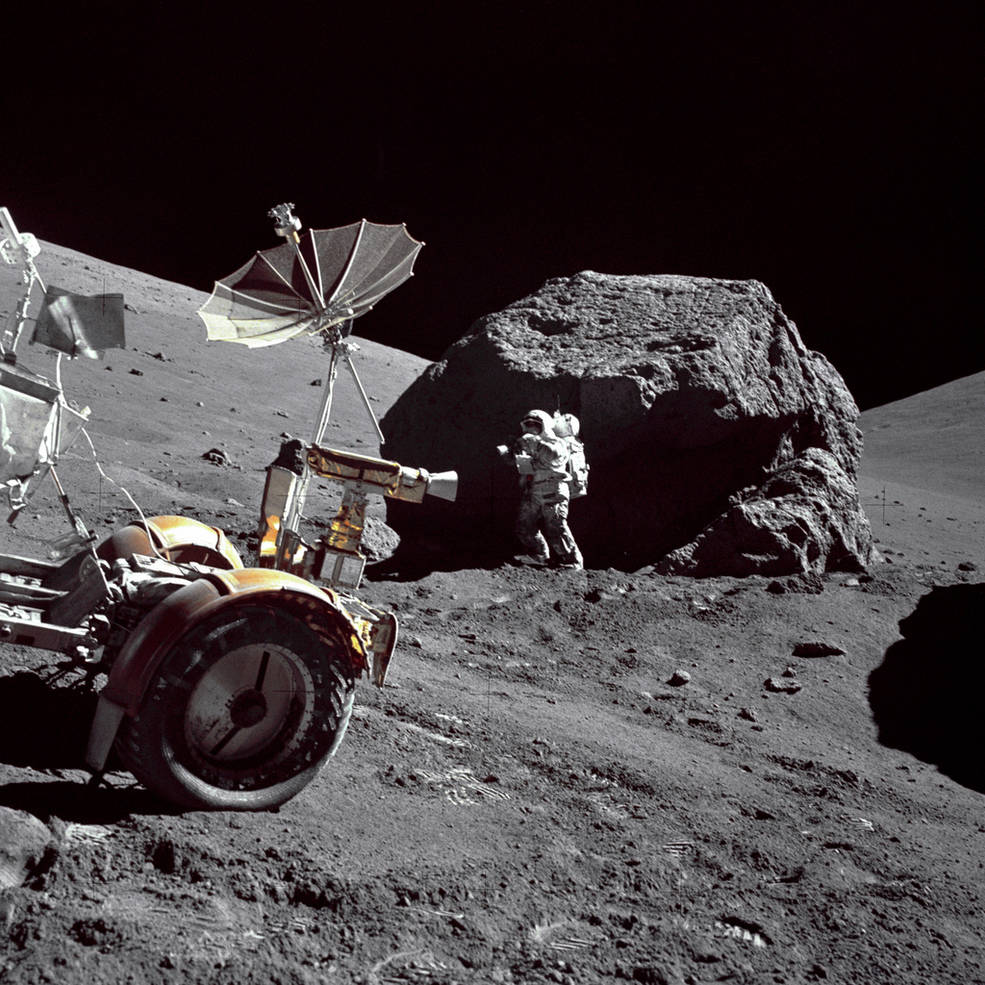 Geologist-Astronaut Harrison H. Schmitt is photographed standing next to a huge, split boulder at Station 6 on the sloping base of North Massif during the third Apollo 17 extravehicular activity (EVA-3) at the Taurus-Littrow landing site. The "Rover" Lunar Roving Vehicle (LRV) is in the left foreground. Schmitt is the Apollo 17 Lunar Module pilot. This picture was taken by Commander Eugene A. Cernan on n December 13, 1972. Image Credit: NASA.