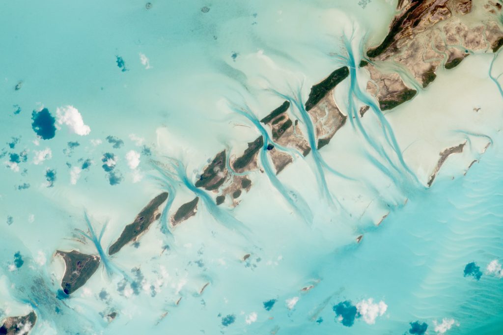 This amazing photograph taken by astronauts on board the International Space Stations shows the Bahamas and another barely visible, yet equally stunning feature, an airplane flying hundreds of kilometers beneath the ISS. Image Credit: NASA.