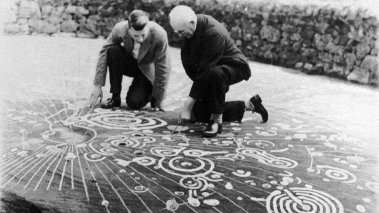 Experts examining the Cochno stone. Image Credit: Royal Commission on the Ancient and Historical Monuments of Scotland.