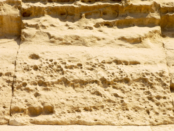 Wżery Tafoni spowodowane nasyceniem wodą morską na pierwszym rzędzie wypolerowanych kamieni licowych Wielkiej Piramidy.  Źródło zdjęcia: Gigal Research.