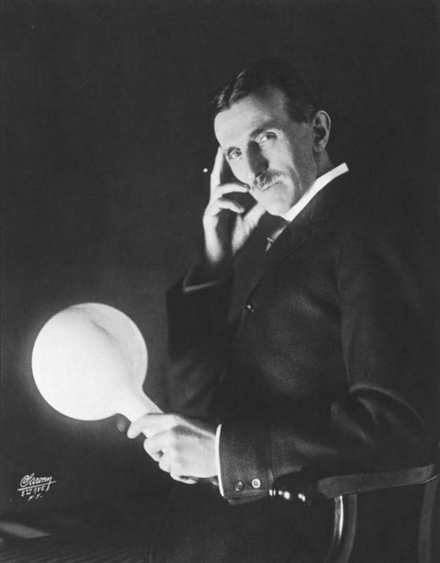 A Photograph of Nikola Tesla holding his gas-filled phosphor-coated wireless light bulb. He developed it in the 1890's.