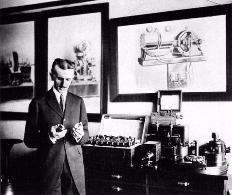 A photograph of Nikola Tesla standing in his New York City Office in 1916.