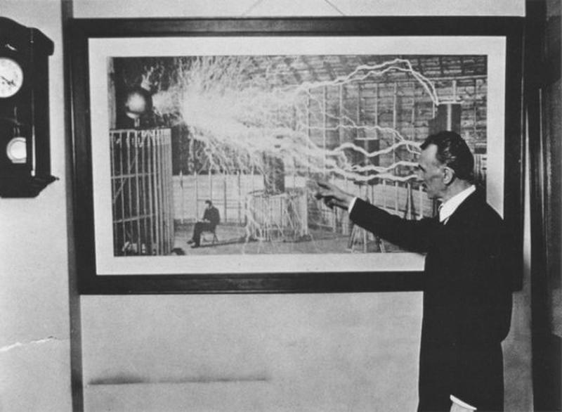 Nikola Tesla in 1916 pointing towards a photograph captured in Colorado Springs in 1899.