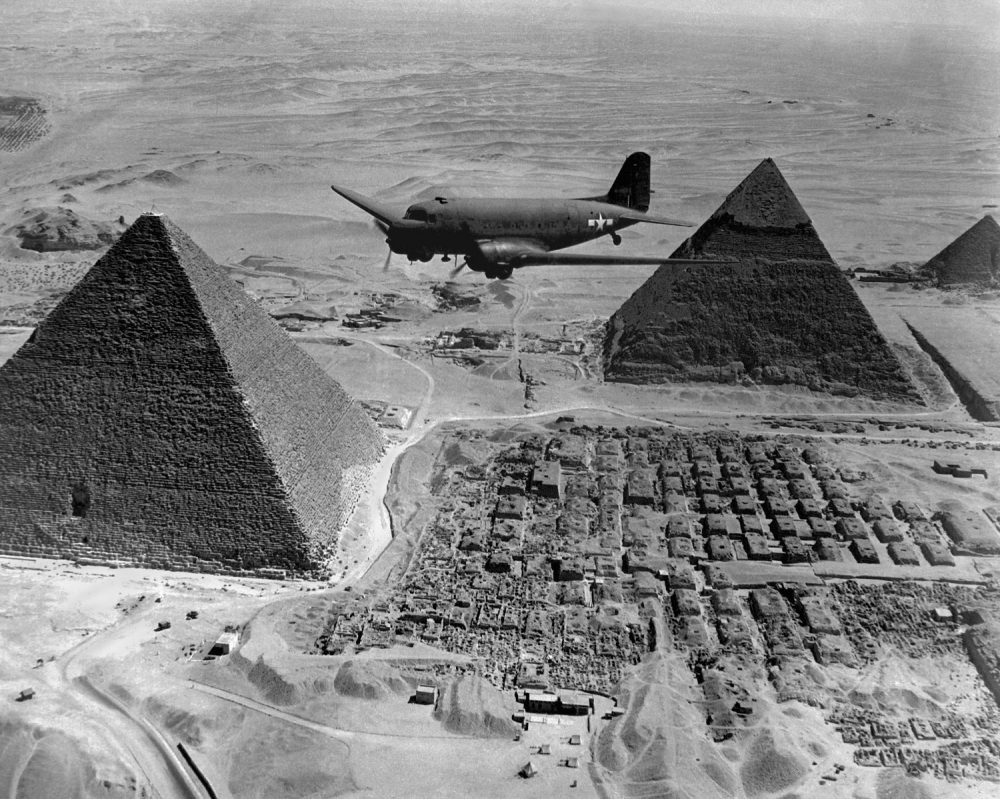 American Air Transport Command plane flies over the pyramids of Egypt. Flights from the U.S. supplied strategic battle zones of North Africa during World War 2. 1943. Shutterstock.