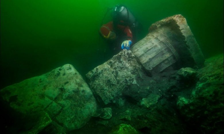 Underwater explorer next to the collumn of a sunken temple. Image Credit: Christoph Gerigk, Franck Goddio / Hilti Foundation.