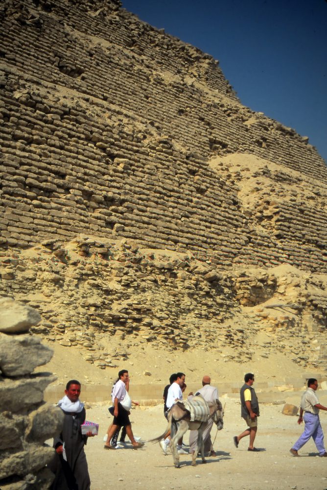 People walking past the Pyramid of Djoser. Although not as big as the Pyramids of Giza that would later be constructed, the Step pyramid is nonetheless a towering structure. Shutterstock.