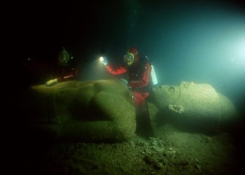 Image showing a diver next to one of the massive statues that now lie submerged in the ancient city of Thonis-Heracleion, at the mouth of the Nile River. Image Credit: Franck Goddio / Hilti Foundation / University of Oxford.