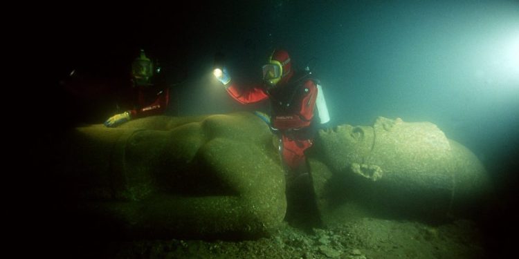 Image showing a diver next to one of the massive statues that now lie submerged in the ancient city of Thonis-Heracleion, at the mouth of the Nile River. Image Credit: Franck Goddio / Hilti Foundation / University of Oxford.