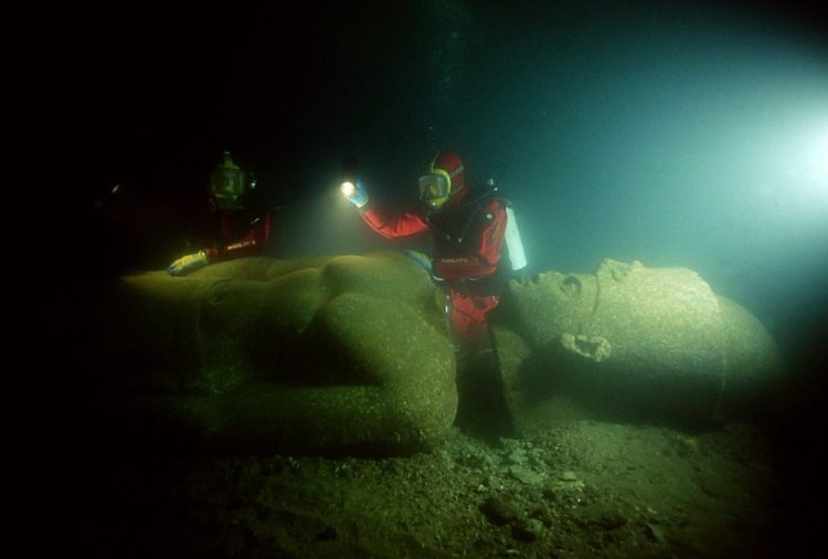 Image showing a diver next to one of the massive statues that now lie submerged in the ancient city of Thonis-Heracleion, at the mouth of the Nile River. Image Credit: Franck Goddio / Hilti Foundation / University of Oxford.