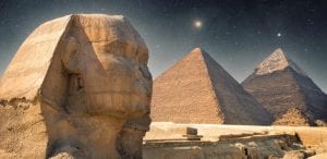 An image showing the The Sphinx, the Great Pyramid and Khafre's Pyramid with the night sky in the background. Shutterstock.