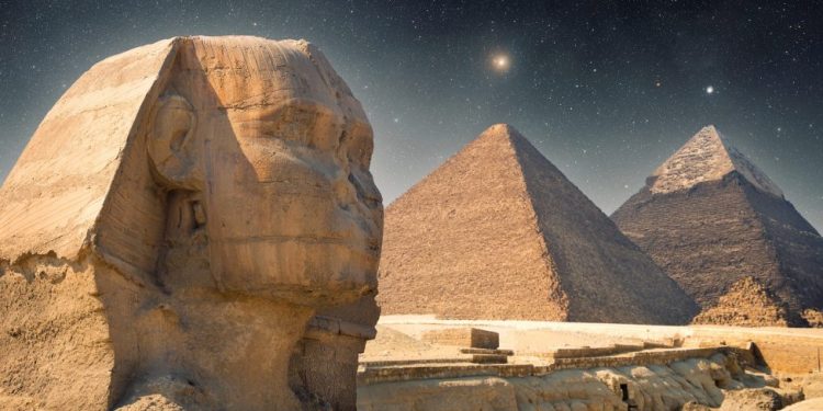 An image showing the The Sphinx, the Great Pyramid and Khafre's Pyramid with the night sky in the background. Shutterstock.