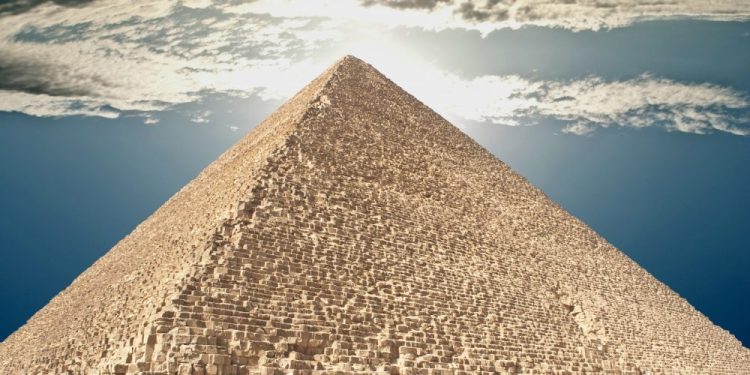 The Great Pyramid of Giza and people climbing its supermassvie stones. Shutterstock.