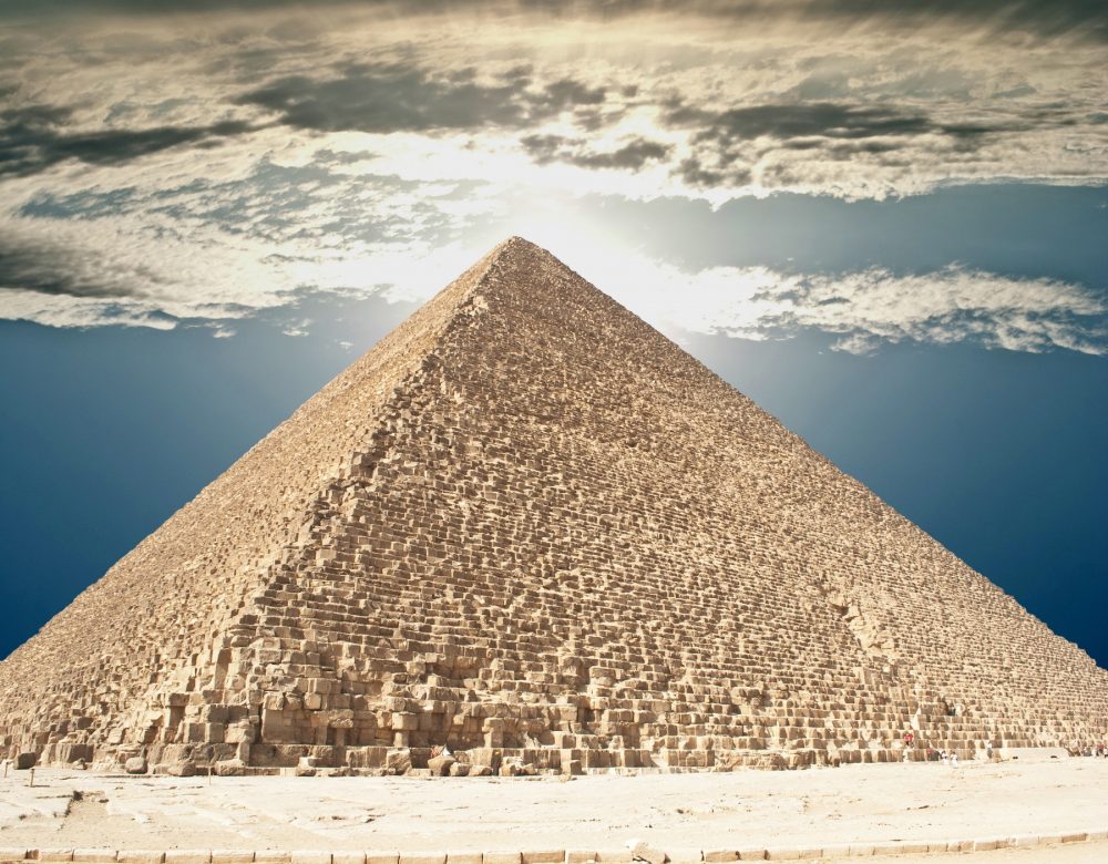 The Great Pyramid of Giza and people climbing its supermassvie stones. Shutterstock.