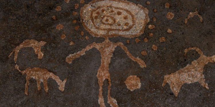 An image of cave art depicting a humanoid with spheres and depictions of what may be animals. Shutterstock.