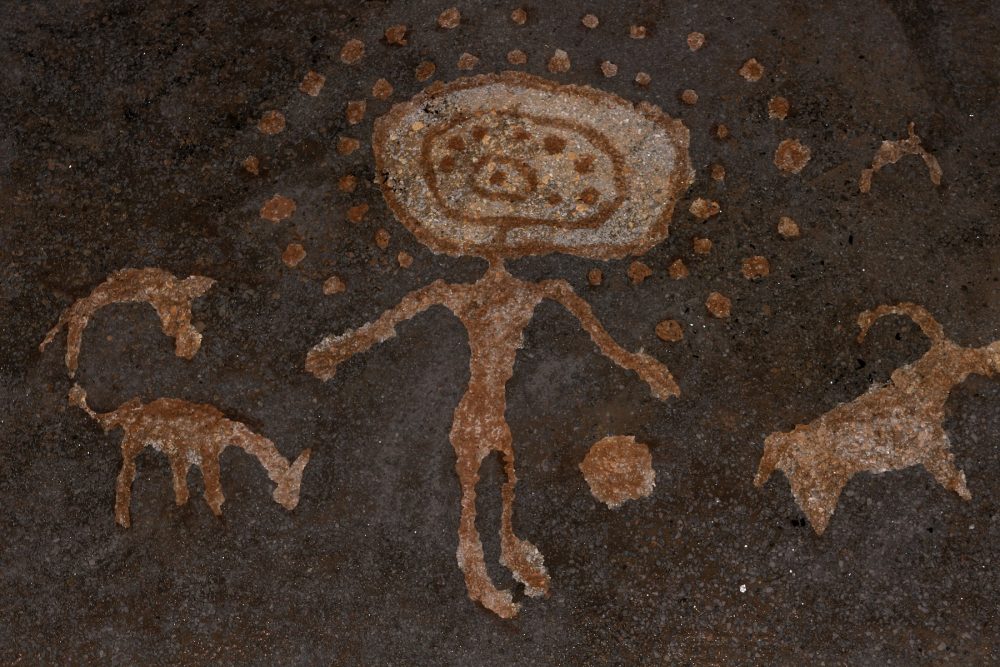 An image of cave art depicting a humanoid with spheres and depictions of what may be animals. Shutterstock.