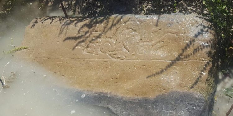 An image showing a half-submerged stone with inscriptions that are thought to date back to the 8th century BC. Image Credit: James Osborne / University of Chicago.