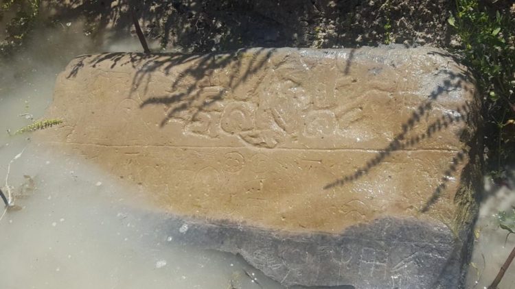 An image showing a half-submerged stone with inscriptions that are thought to date back to the 8th century BC. Image Credit: James Osborne / University of Chicago.