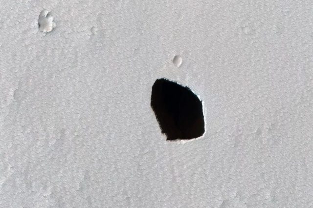 An image of a dark pit on the surface of Mars. Image Credit: NASA/JPL/University of Arizona.