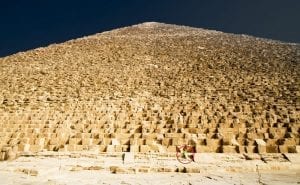 A view of the massive stones that make up the core of the Great Pyramid of Giza. Notices the person sitting on one of the stones. Shutterstock.