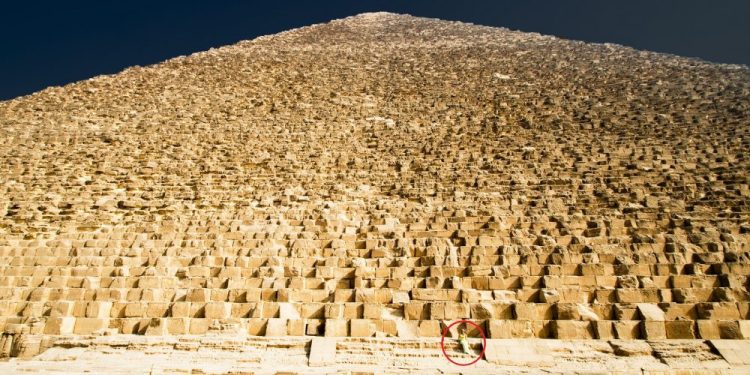 A view of the massive stones that make up the core of the Great Pyramid of Giza. Notices the person sitting on one of the stones. Shutterstock.