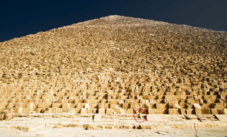 A view of the massive stones that make up the core of the Great Pyramid of Giza. Notices the person sitting on one of the stones. Shutterstock.