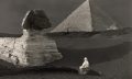 A view of the Sphinx still covered in sand. Behind it, the Great Pyramid.