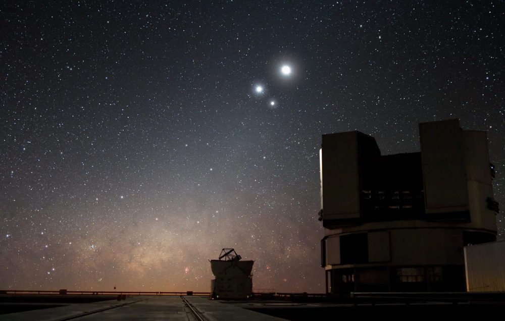 An image of the night sky over ESO's Very Large Telescope (VLT) observatory at Paranal. In the image, the Moon shines along with two bright companions Venus and Jupiter. Image Credit: Wikimedia Commons.