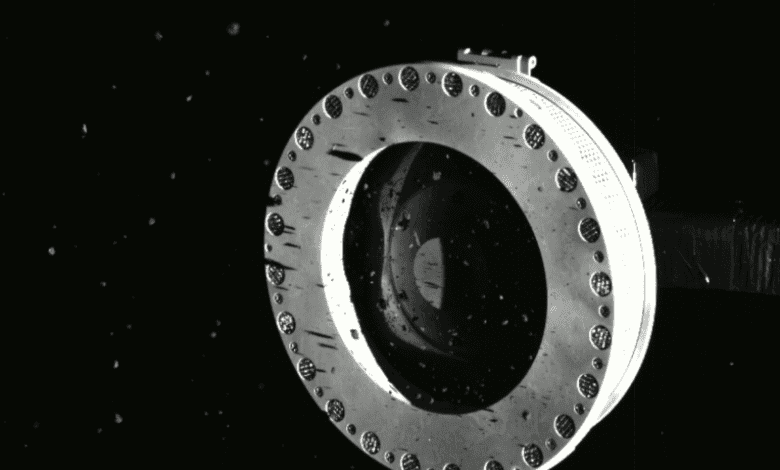 A screenshot showing material from the surface of Bennu entering the Touch-And-Go Sample Acquisition Mechanism. Image Credit: NASA.