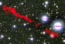 In this image, you can see one of the giant radio galaxies (MGTC J100016.84+015133.0) in red and a cosmic background as you would see it in optical light. Credit: I. Heywood, University of Oxford / Rhodes University / South African Radio Astronomy Observatory / CC BY 4.0.