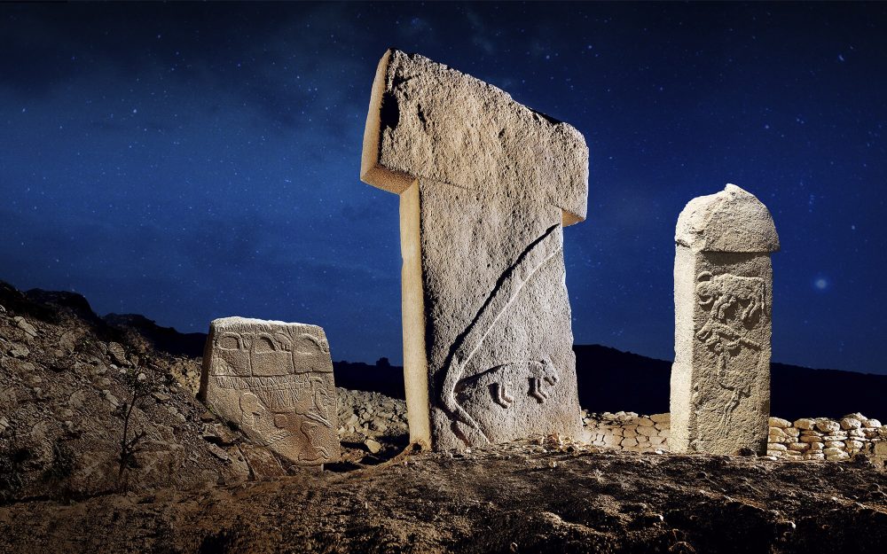 One of the famous T-shaped pillars of Gobekli Tepe between two other curious pillars with illustrations. On the left one, you see the famous "handbag of the Gods", an image seen in many ancient sites around the world. Credit: Gulcan Acar