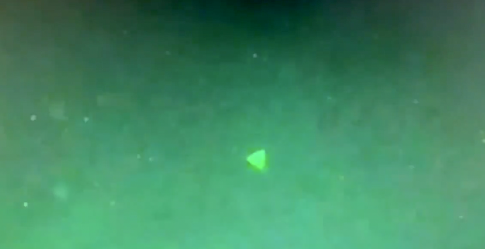 A screenshot of the video allegedly showing a pyramid-shaped UFO hovering above a US Navy ship. Image Credit: Jeremy Corbell / Twitter.