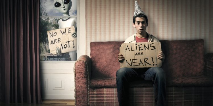 Guy holding a cardboard saying aliens are near.