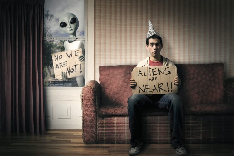 Guy holding a cardboard saying aliens are near.