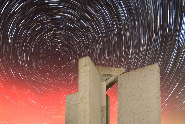 A photograph of the Georgia Guidestones and start rails in the sky. Depositphotos.