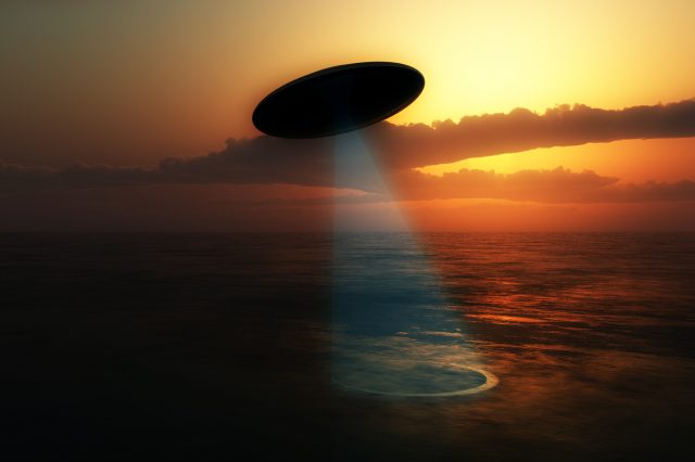 Illustration of a UFO absorbing water from a lake. Depositphotos.