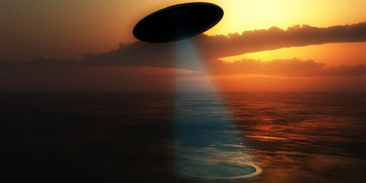 Illustration of a UFO absorbing water from a lake. Depositphotos.