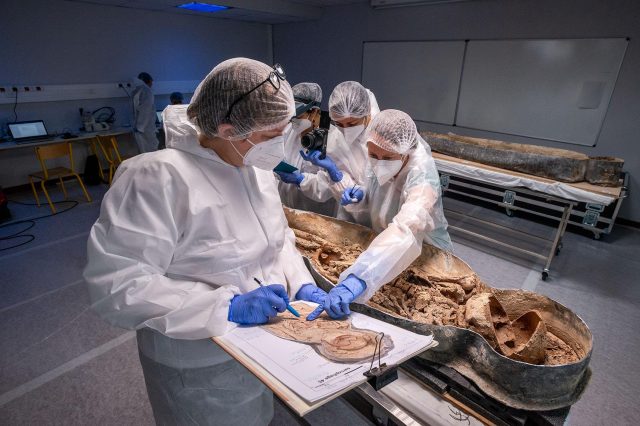 Scientists inspecting the remains of a man with a sawed-off elongated skull, found under Notre Dame. Credit: Denis Gliksman, Inrap