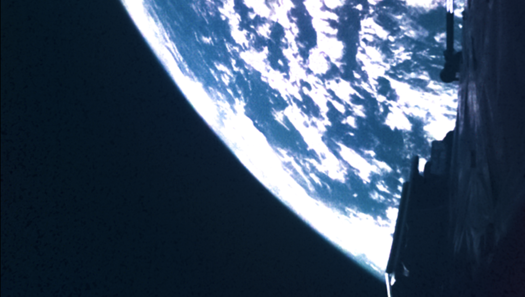 A photograph showing part of the JUICE spacecraft and Earth in the background. ESA/JUICE.