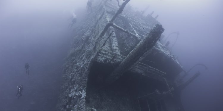 Divers exploring a shipwreck. YAYIMAGES.