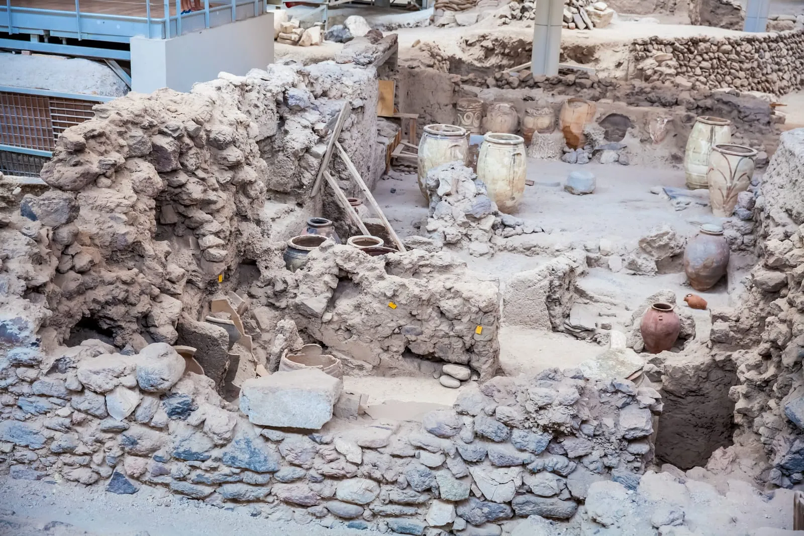 Clay vessels rest inside a partially excavated room, surrounded by stone walls and rubble. The sharp preservation of everyday objects highlights the moment in time when the city was suddenly buried.