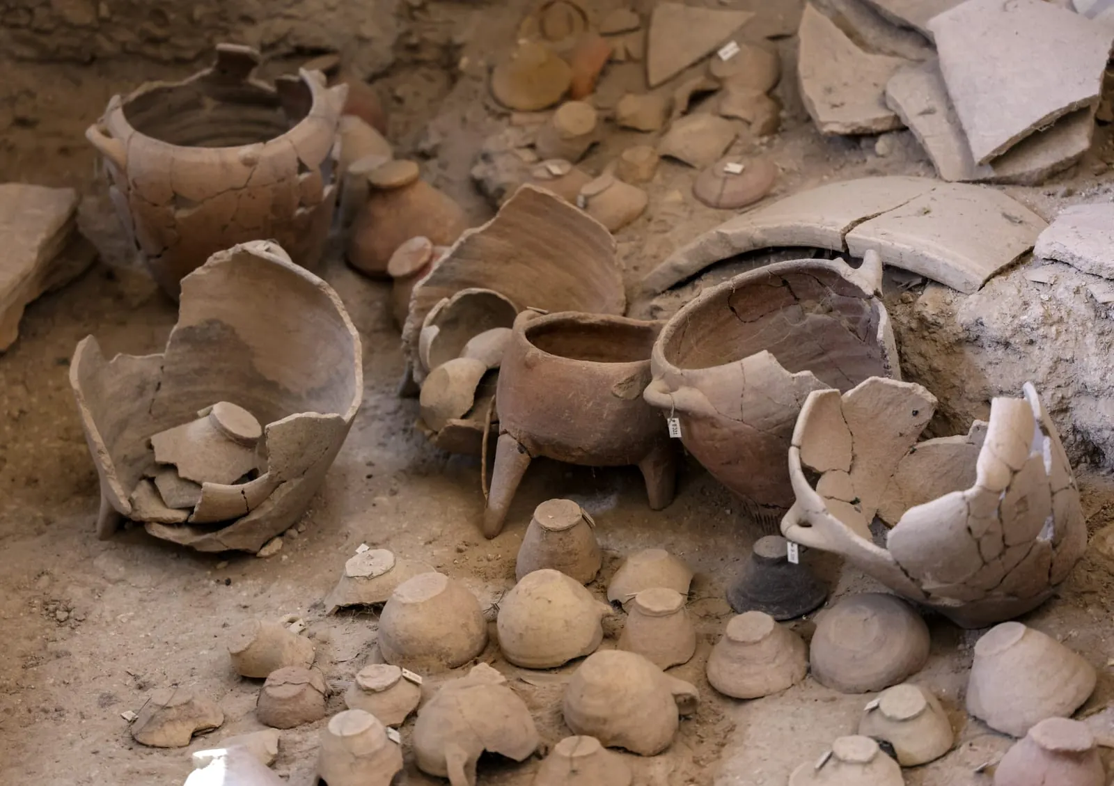 A cluster of broken ceramic vessels lies undisturbed in the soil of Akrotiri. Many still hold their original shapes despite centuries underground, offering insight into the cooking and food storage practices of the city's residents.