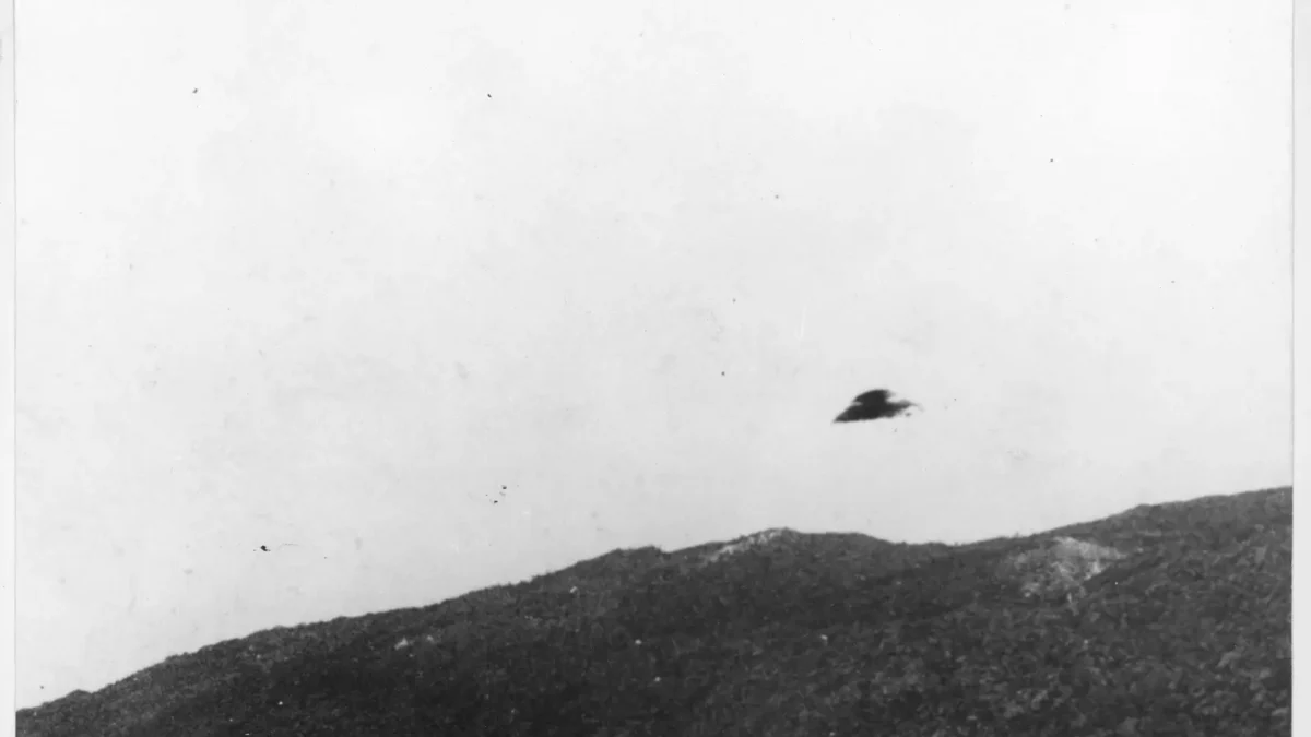 Historic black-and-white National Archives UAP record showing a dark object above a ridge