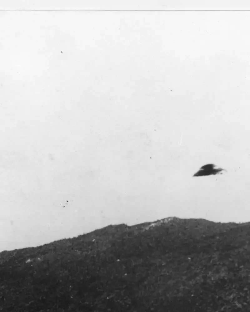 Historic black-and-white National Archives UAP record showing a dark object above a ridge