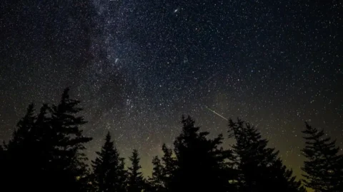 A bright meteor streaking through Earth's atmosphere above a dark landscape