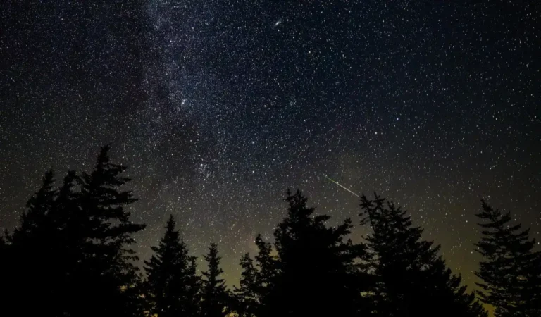 A bright meteor streaking through Earth's atmosphere above a dark landscape