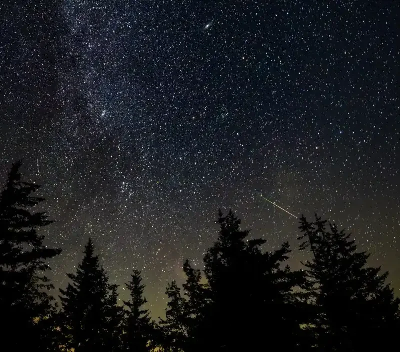 A bright meteor streaking through Earth's atmosphere above a dark landscape