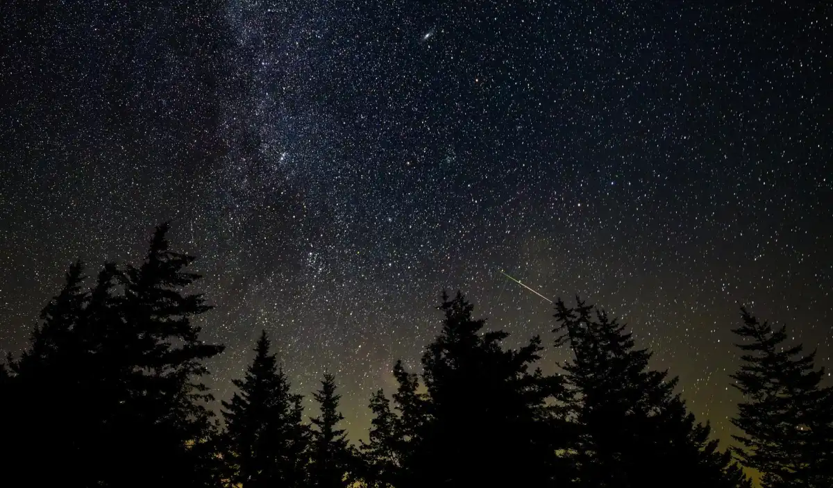 A bright meteor streaking through Earth's atmosphere above a dark landscape