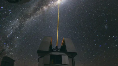 A green laser beam aimed toward the center of the Milky Way above an observatory